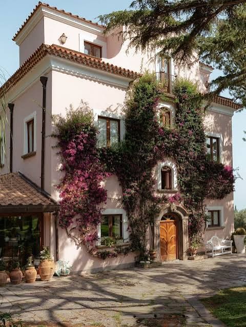 The villa's façade covered in climbing flowers